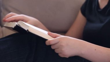 Genç kadın İncil okuma kanepede rahatlatıcı