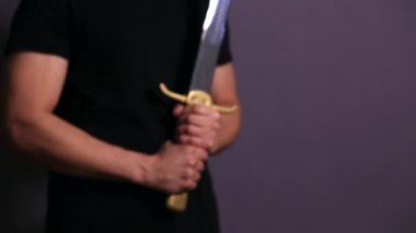 Casually dressed strong young guy standing ready with his sword