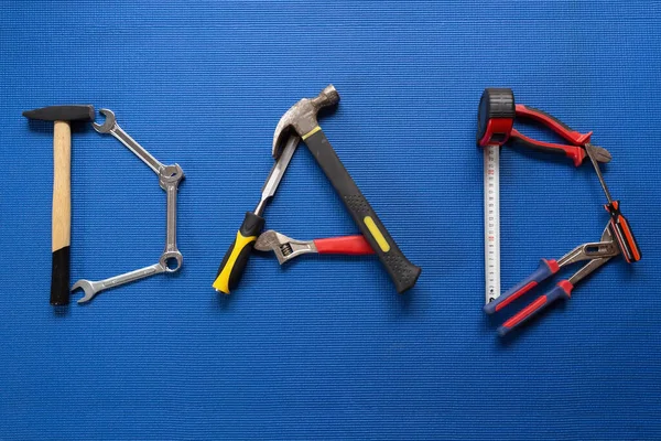 The word dad spelled out with different hand tools on Blue background