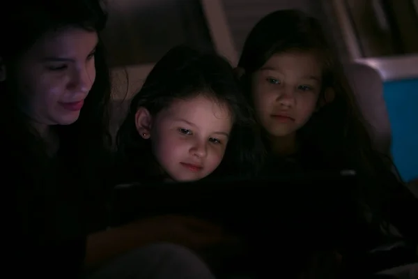 Young Mother watching a show with her children at home on in the dark