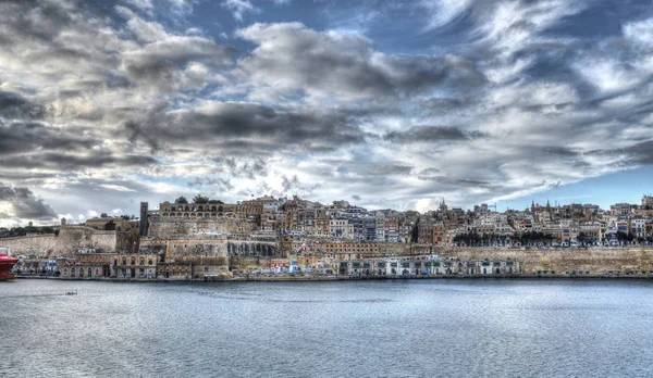 Widok od strony miasta Vittariosa na mury obronne stolicy Malty La Valetta przez zatoke Grand Harbour. Po lewej limanı w srodku ogrody Barraca.