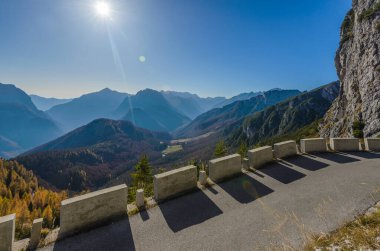 Sonbaharda Mangart 'a giden eski asfalt yol. Yıpranmış beton yığınları ve arka planda güzel bir dağ manzarası..