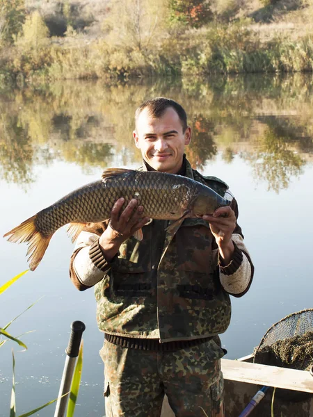 Fisherman With fish Mirror Carp. Fishing on river on autumn — Stock Photo, Image