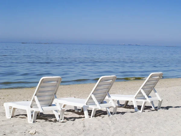 Drei Liegestühle an einem einsamen Strand Stockbild
