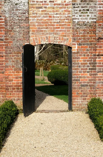 Una Porta Legno Nera Muro Mattoni Aperto Giardino Oltre — Foto Stock