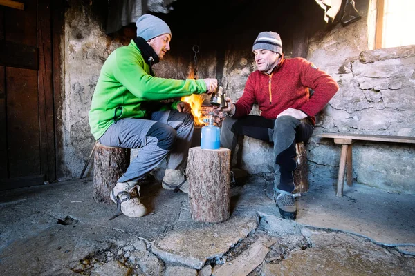 Freunde sitzen und trinken vor dem Kamin in den Bergen — Stockfoto