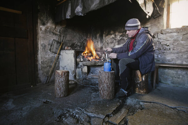 man wam front of the fireplace in the mountains