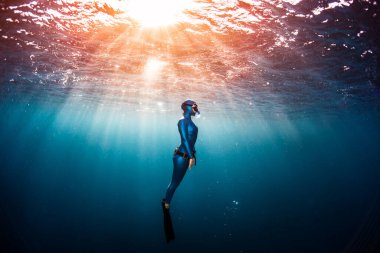 Kadın serbest dalgıç tropik açık denizde derinlerden yükseliyor.