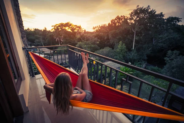 年轻女子在阳台上的吊床上享受日落的悠闲 — 图库照片