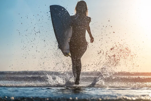 年轻女人带着冲浪板跑 溅了很多水 — 图库照片