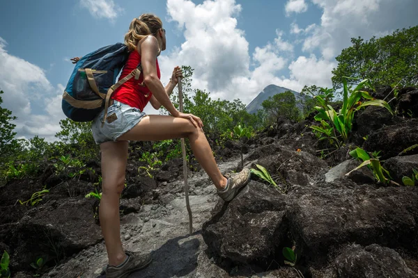 年轻的女徒步旅行者站在小径上 观望地平线上的火山 — 图库照片
