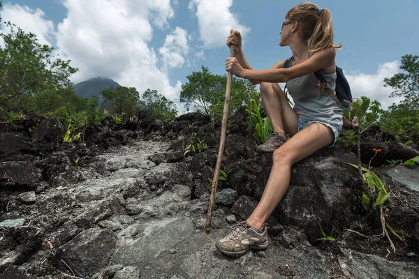 Genç Bir Kadın Volkanik Patikada Yürüdükten Sonra Kayanın Üzerinde Dinleniyor — Stok fotoğraf