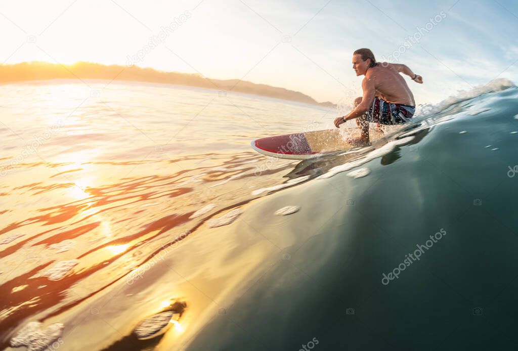 Surfer rides the perfect ocean wave at sunrise