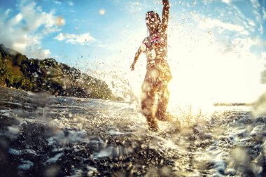 Denizde bir sürü su sıçramasıyla eğlenen genç bir kadın.