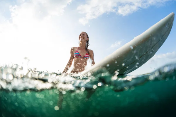 快乐的女人坐在海里的冲浪板上 — 图库照片