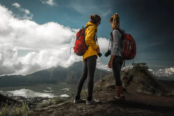 写真カメラを持つ2人の女性ハイカーが丘の上に立って谷の景色を楽しむ — ストック写真