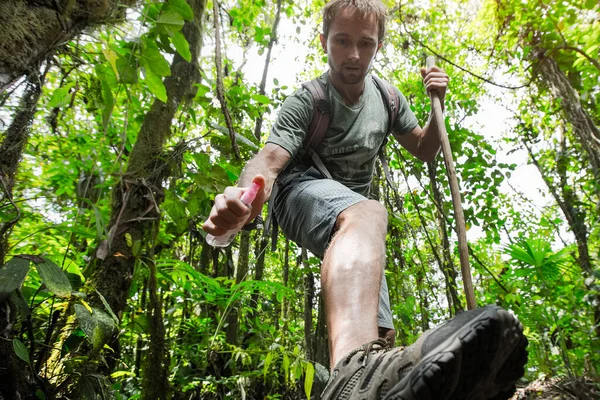 徒步旅行者在茂密的热带森林里用驱蚊剂护腿 — 图库照片