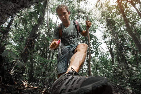 鬱蒼とした熱帯雨林で彼の足に撥水剤を適用するハイカー — ストック写真