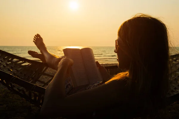 女は熱帯の浜でハンモックで本を読む — ストック写真