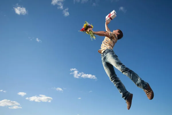 年轻人拿着礼盒和鲜花在空中飞舞 — 图库照片