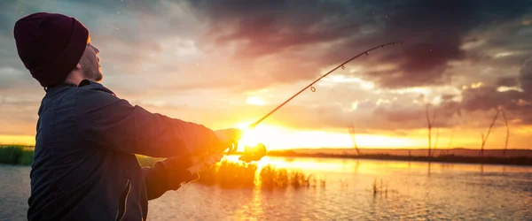 日没時に湖で釣りをする男 — ストック写真