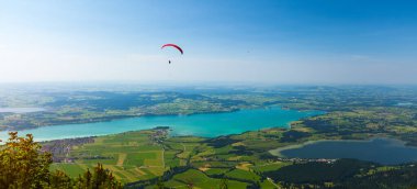 Paraglider, gölleri ve kasabaları olan yeşil vadinin üzerinde uçuyor. Fussen, Almanya 'da bir şehirdir.