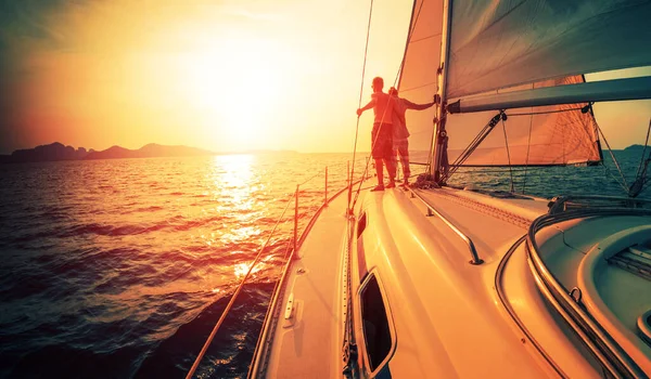 年轻夫妇享受着在热带海域航行的帆船上的落日 — 图库照片