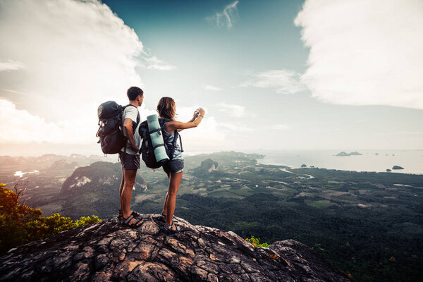 Два туриста отдыхают на вершине горы с прекрасным видом