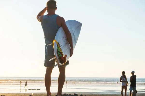サーフボードを持つ男はビーチで海サーフィンの状態をチェックします — ストック写真