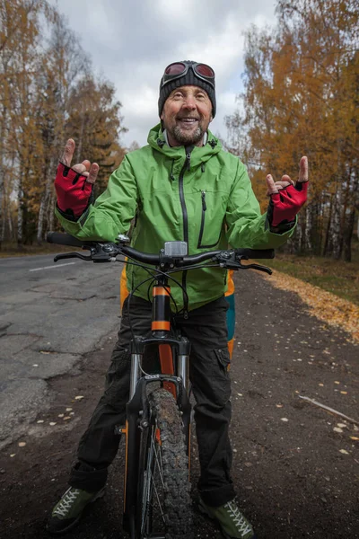 アスファルトの秋の道路に彼のロードバイクと成熟した自転車観光客 — ストック写真