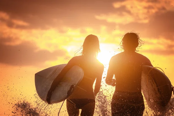 Några Surfare Springer Med Brädor Och Massor Stänk Vid Solnedgången — Stockfoto