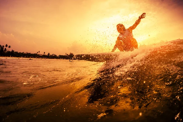 年轻的冲浪运动员在日落时乘风破浪 — 图库照片