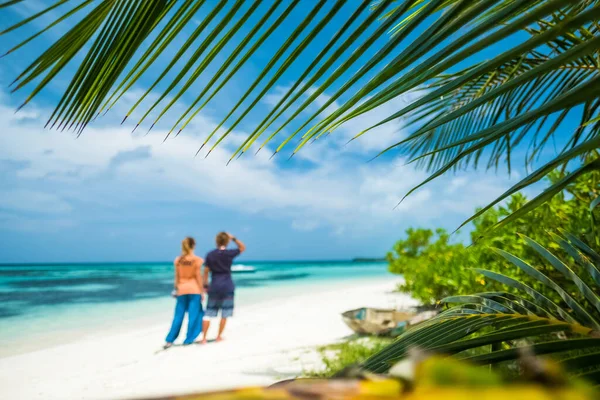 Ett Par Står Den Tropiska Stranden Fokusera Palmblad Förgrunden — Stockfoto