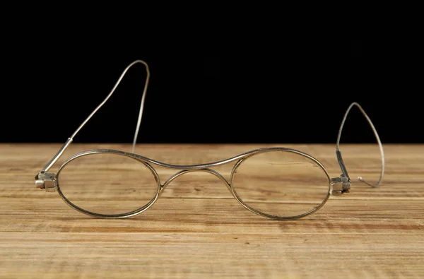 Óculos velhos em um fundo preto — Fotografia de Stock
