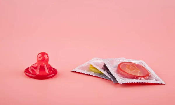 粉红的底色上的红避孕套关闭 — 图库照片
