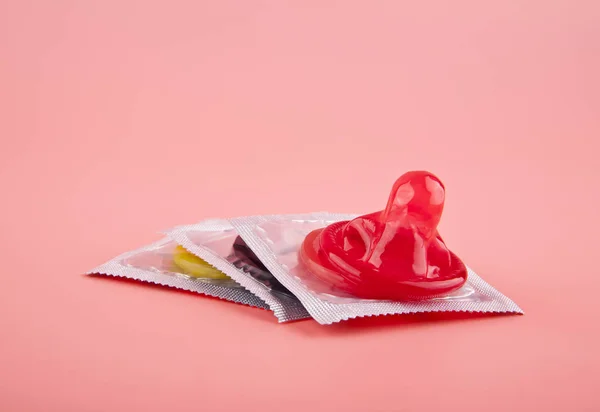 Röd kondom på en rosa bakgrund närbild — Stockfoto