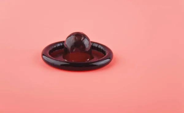 Zwart condoom op roze achtergrond closeup — Stockfoto