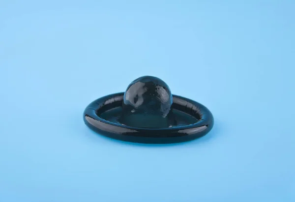 Preservativo negro sobre fondo azul — Foto de Stock