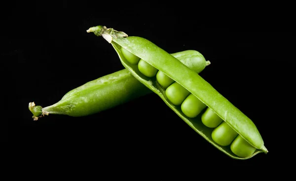 Ervilhas verdes em um fundo preto closeup — Fotografia de Stock