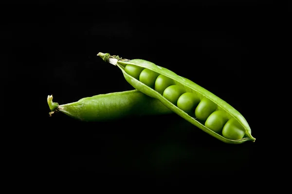 Ervilhas verdes em um fundo preto — Fotografia de Stock