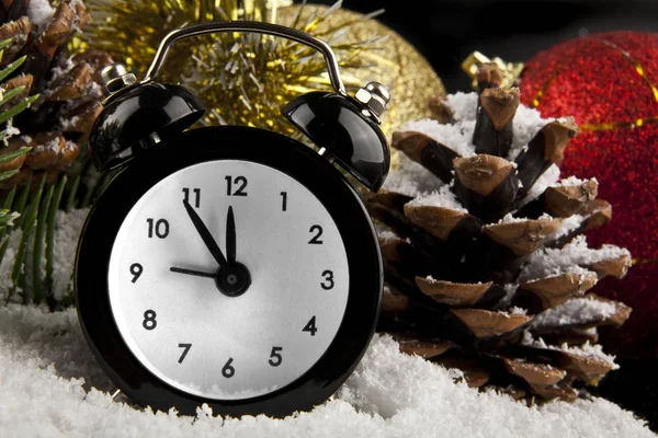 Reloj, cono, decoraciones navideñas y nieve sobre un fondo negro —  Fotos de Stock