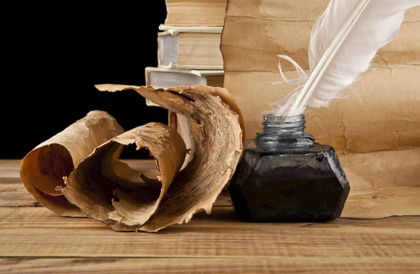 Old paper, books and inkwell with a pen on a black background — Stock Photo, Image