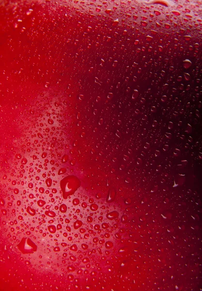 Капли воды на фоне красного яблока — стоковое фото
