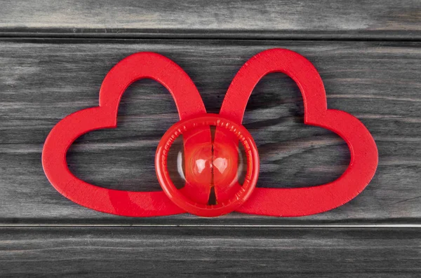 Cuori rossi e preservativo su uno sfondo di legno — Foto Stock