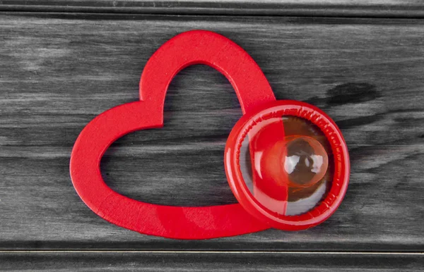 Cuori rossi e preservativo su uno sfondo di legno — Foto Stock