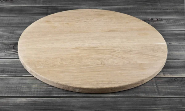 Rundes Pizzabrett auf Holzgrund — Stockfoto