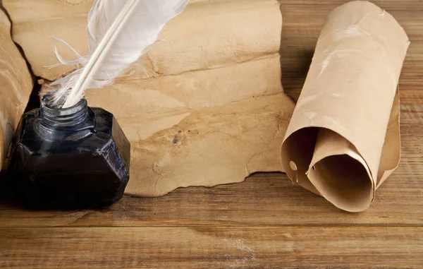 Un papel viejo, un tintero y una pluma sobre un fondo de madera — Foto de Stock