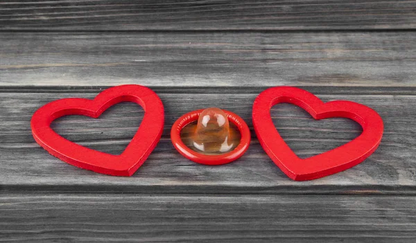 Rode harten en condoom op een houten achtergrond — Stockfoto