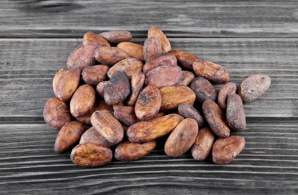 Granos de cacao sobre un fondo de madera — Foto de Stock