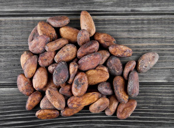 Granos de cacao sobre un fondo de madera — Foto de Stock